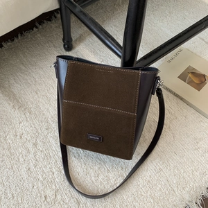 Détail du sac seau en daim et cuir marron avec plaque argentée et fine bandoulière