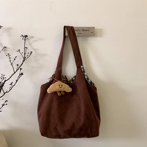 Détail d'un cabas en daim marron avec doublure à damier et accessoire peluche mignon