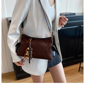 Close-up of vintage brown suede bag with unique beaded tassels and wood accents