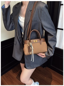 Detail of brown contrast bucket bag featuring gold lock and chocolate charm
