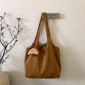Détail du sac cabas en daim marron avec doublure à carreaux et breloque croissant
