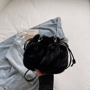 Détail d'un sac seau en fausse fourrure noire avec texture douce et boucles argentées