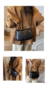 Gros plan d'un sac bandoulière demi-lune en cuir noir brillant avec logo doré et pompon