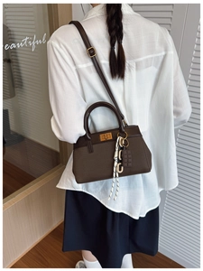 Detail view of the brown leather bucket bag with gold hardware and creative bag charm