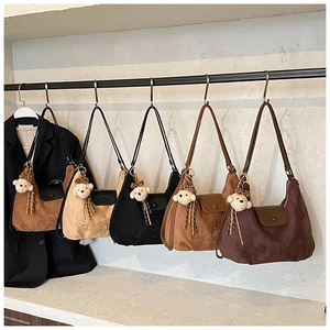Detailed row of five suede shoulder bags in various colors with cute bear pendants