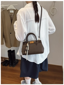 Detail of brown lychee leather handbag featuring a gold square twist lock and accessories