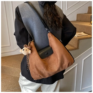 Detail of a brown suede tote bag featuring cartoon embossing and a cute bear charm