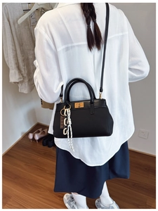 Detail of black textured leather bucket bag with gold lock and adjustable strap