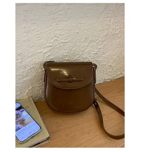 Detail of a vintage dark brown semi-circle flap bag with a leather bow and oil wax finish