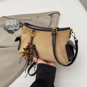 Detail of khaki suede handbag featuring wooden bead tassels and contrast leather trim details