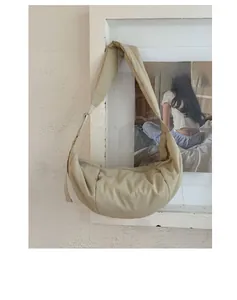 Detailed view of quilted bubble nylon fabric and adjustable wide strap on beige bag