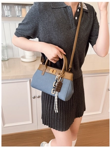 Detailed side view of vintage contrast leather and denim handbag with chain pendant
