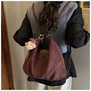 Detail of vintage brown suede backpack featuring a cute teddy bear charm and embossed pattern