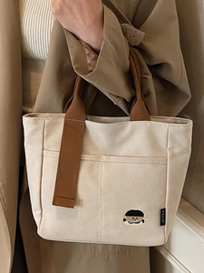 Sac cabas minimaliste en toile blanc cassé avec anses brunes et détail brodé