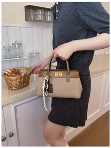 Detail of khaki canvas handbag with brown leather trim and golden twist-lock closure