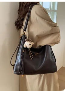 Detail view of large dark brown leather tote bag with a cute teddy bear charm