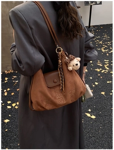 Close-up of brown suede tote bag featuring cat embroidery and a cute teddy bear charm