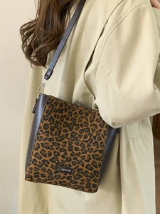 Sac seau chic à imprimé léopard et cuir marron porté par un mannequin en trench