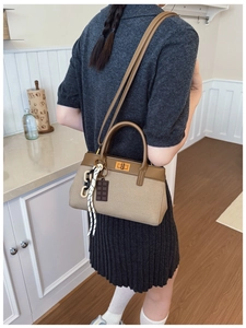 Detail of canvas handbag with brown leather flap and stylish chocolate charm in home setting