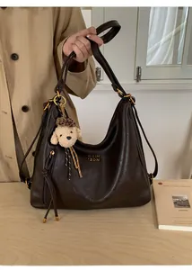 Close-up of brown leather hobo bag with gold logo and cute plush dog charm detail