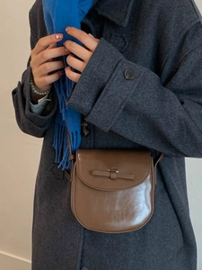 Vintage brown leather crossbody bag with a stylish bow decoration and minimalist round design