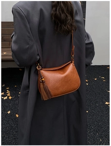 Vue détaillée du sac demi-lune en cuir caramel avec franges décoratives et perles noires