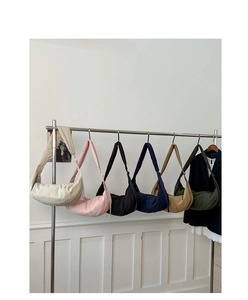 Row of colorful quilted nylon crescent bags hanging on metal hangers against white wall