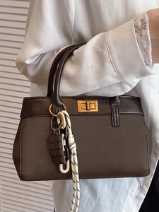 Brown canvas bucket bag with leather trim and chocolate charm pendant in a lifestyle setting