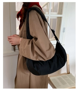 Close-up of black nylon crescent bag with adjustable wide shoulder strap on model