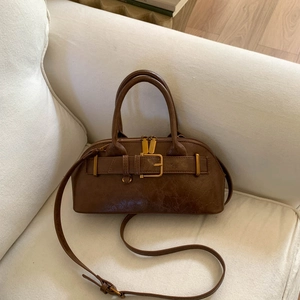 Close-up of brown leather handbag with decorative strap and vintage gold hardware