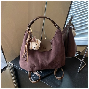 Detail of vintage brown suede hobo bag featuring a cute rabbit relief and bear charm