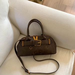 Detail of vintage brown leather handbag featuring golden buckle and adjustable strap