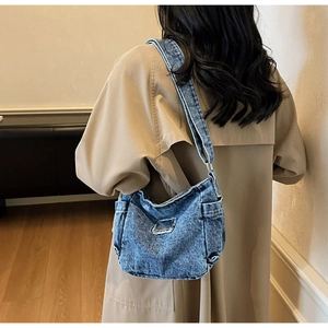 Retro washed denim crossbody bag featuring side pockets and vintage distressed details