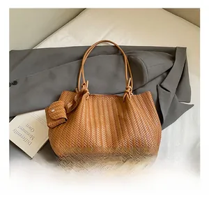 Detail of a brown woven tote bag with matching pouch and stylish shoulder strap
