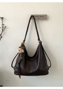 Close-up of brown oiled leather Hobo bag featuring golden logo and leopard bear charm