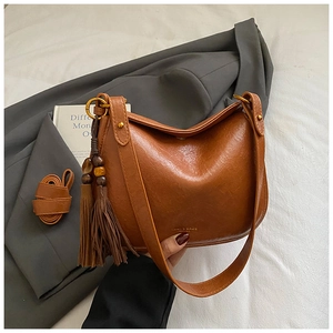 Détail du sac bandoulière marron mat avec pompon décoratif et perles en bois