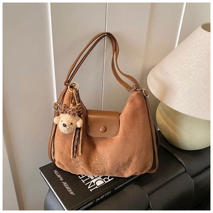 Detail view of brown suede crescent bag with cute bear charm and animal embroidery