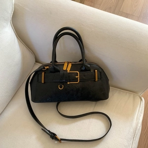 Close-up of black pebble leather texture and vintage gold hardware on the handbag