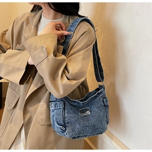 Detail of vintage blue denim shoulder bag with distressed patch and side pocket