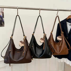 Detailed view of three vintage large capacity hobo bags with bear charms and tassels