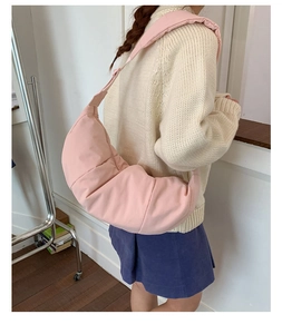 Detail showing pink quilted crescent bag with wide shoulder strap worn by a model