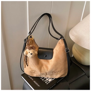 Detail of suede shoulder bag with cartoon embossed pattern and cute plush dog pendant