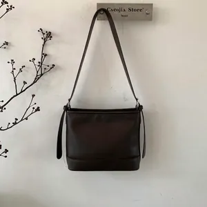 Detaillierte Seitenansicht einer minimalistischen kaffeebraunen Ledertasche mit Zierband