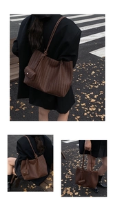 Detail view of deep brown woven tote bag with matching mini pouch and urban street style