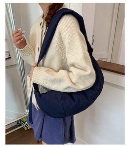Detail view of navy blue quilted crescent bag showing the puffy texture and wide strap
