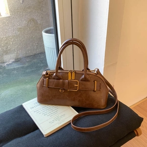 Detail of vintage brown boston handbag featuring aged texture and metal buckle decor