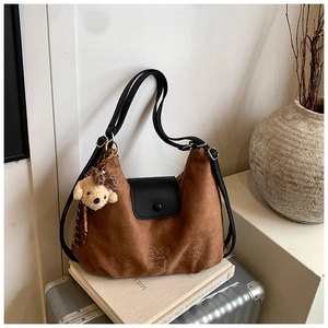 Detail of vintage brown suede tote bag with black leather handle and plush puppy pendant