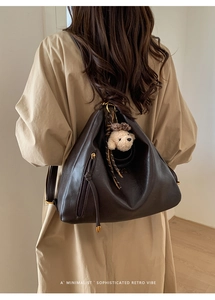 Detail of dark brown faux leather tote with dog charm and side zipper pocket