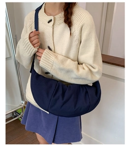 Close-up of navy blue nylon dumpling bag with pleated texture and wide shoulder strap