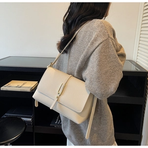 Detail view of cream white pebbled leather bag with gold buckle on a shoulder model